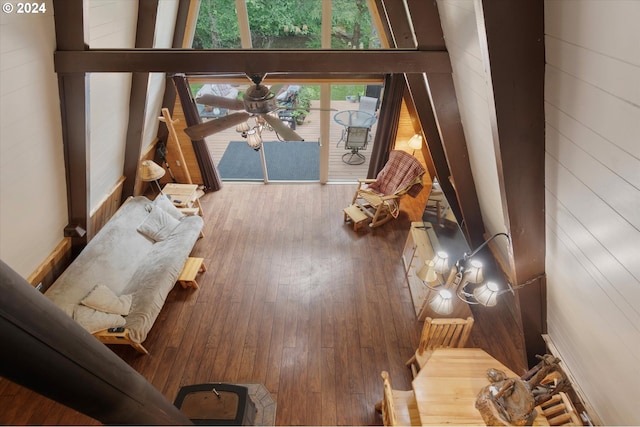 living area featuring hardwood / wood-style flooring, ceiling fan, and wooden walls