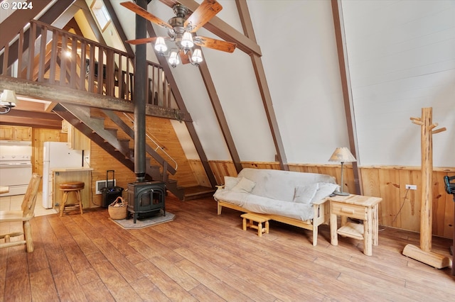 living area with a wood stove, wood walls, beamed ceiling, and light wood finished floors