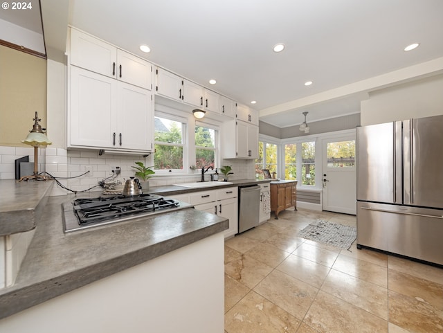 kitchen featuring white cabinets, stainless steel appliances, tasteful backsplash, and sink