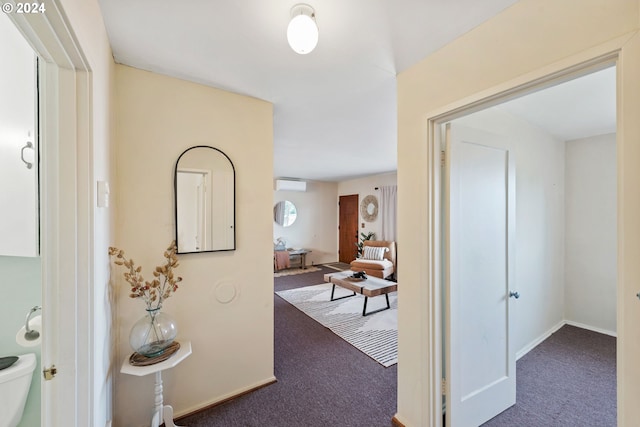 hallway with dark carpet and a wall mounted air conditioner