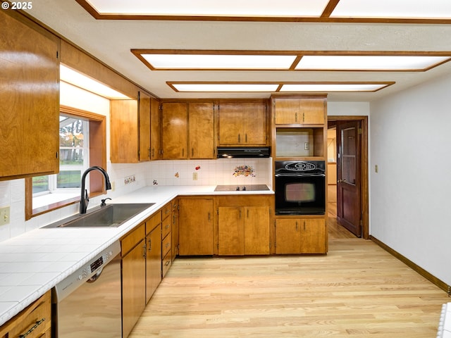 kitchen featuring sink, tile countertops, light hardwood / wood-style floors, backsplash, and black appliances