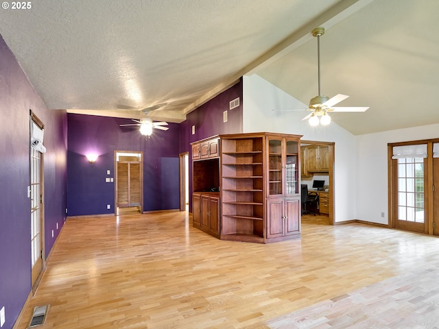 unfurnished living room featuring a textured ceiling, light wood-type flooring, ceiling fan, high vaulted ceiling, and beam ceiling