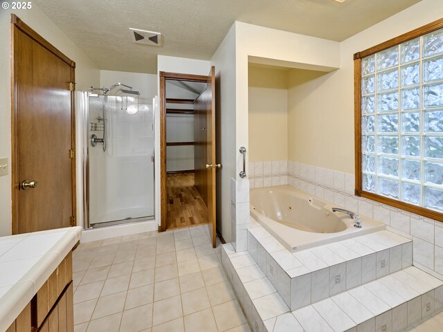 bathroom featuring a textured ceiling, separate shower and tub, and tile patterned floors