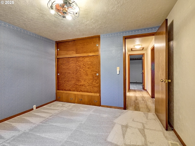 unfurnished bedroom with a textured ceiling and light colored carpet