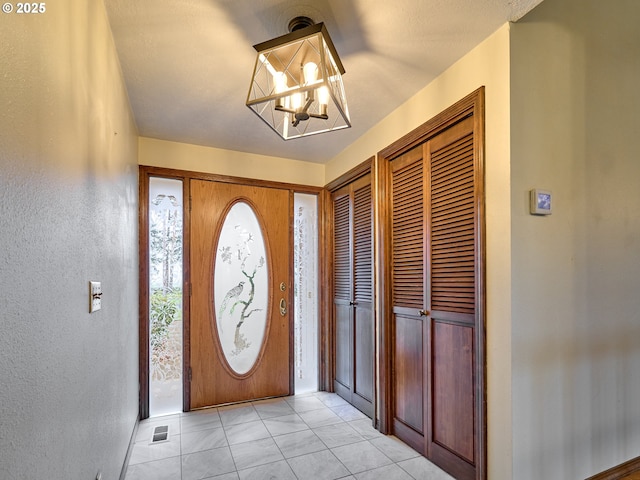 entrance foyer with light tile patterned flooring and a chandelier