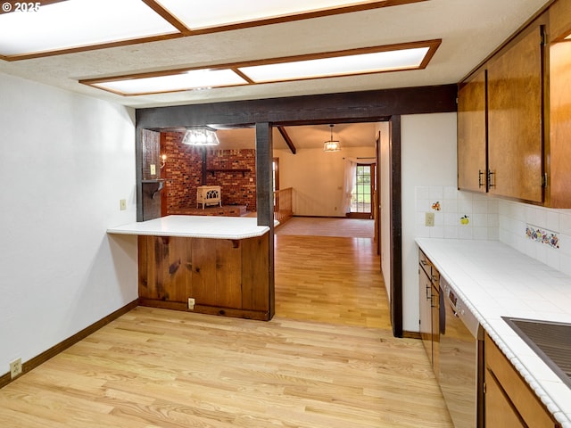 kitchen with hanging light fixtures, dishwasher, light hardwood / wood-style floors, and decorative backsplash