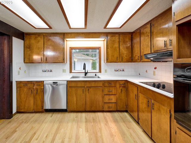 kitchen featuring light wood-type flooring, black appliances, tasteful backsplash, and sink