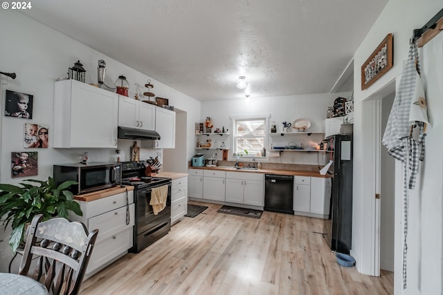 kitchen with under cabinet range hood, open shelves, white cabinets, black appliances, and light wood finished floors