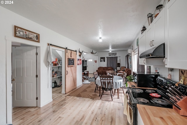 kitchen with electric stove, white cabinetry, light hardwood / wood-style flooring, wooden counters, and a barn door