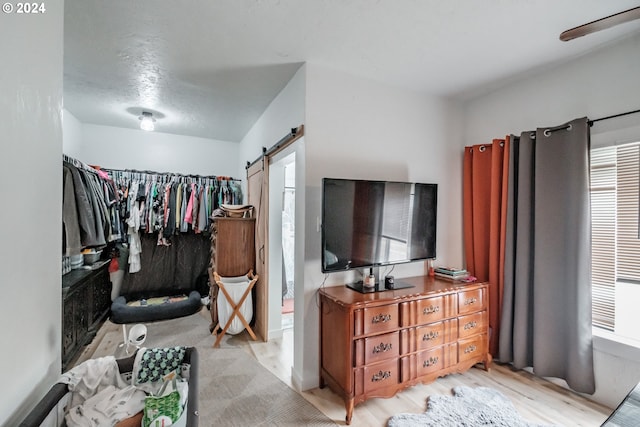 bedroom with light wood-type flooring, a closet, and a barn door