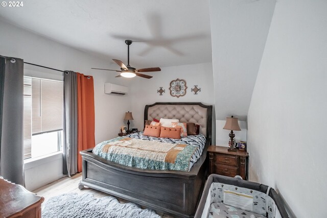 bedroom with ceiling fan, a wall unit AC, and light hardwood / wood-style flooring