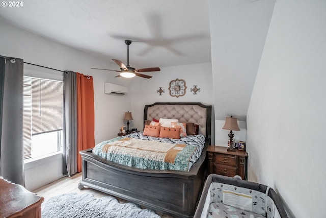 bedroom with light wood-style floors, ceiling fan, and a wall mounted air conditioner