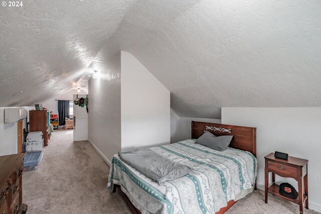 carpeted bedroom with a textured ceiling and vaulted ceiling