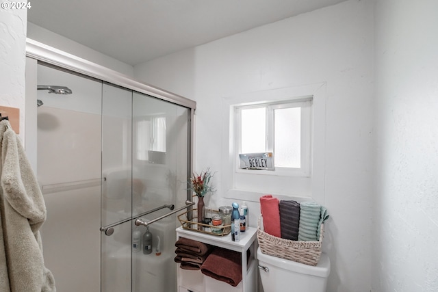 bathroom featuring toilet and a shower with door