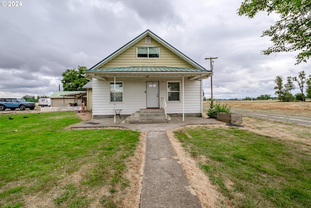 bungalow-style home with metal roof, a front lawn, and a standing seam roof