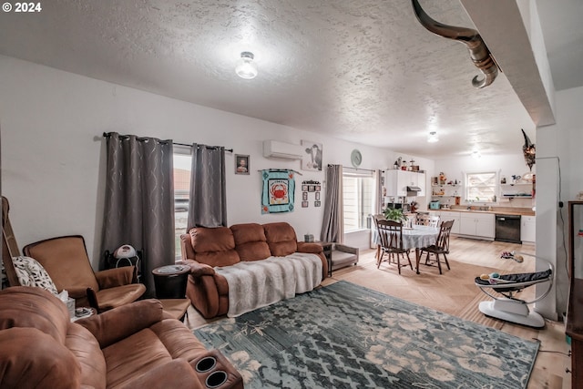 living area featuring light wood-style flooring, a textured ceiling, and an AC wall unit