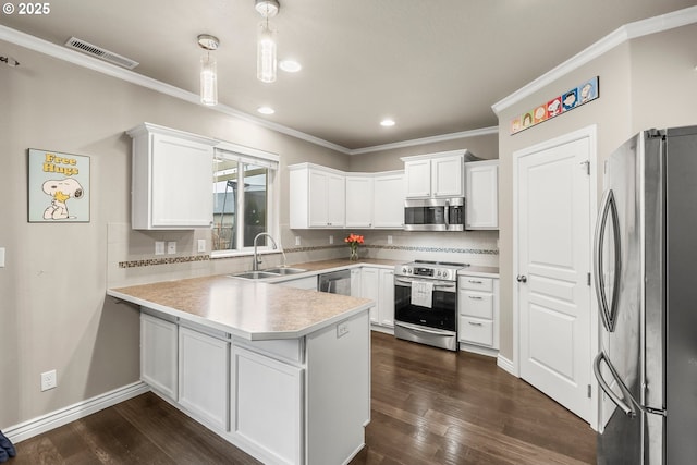 kitchen featuring sink, appliances with stainless steel finishes, white cabinetry, decorative light fixtures, and kitchen peninsula