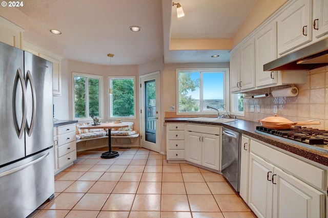 kitchen with light tile patterned floors, appliances with stainless steel finishes, sink, decorative backsplash, and white cabinetry