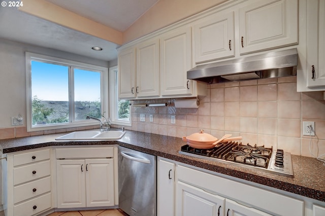 kitchen with light tile patterned floors, appliances with stainless steel finishes, tasteful backsplash, sink, and white cabinetry