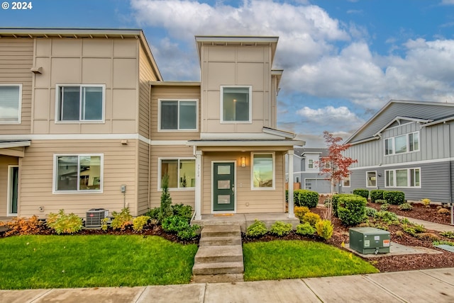 view of property featuring a front lawn and cooling unit