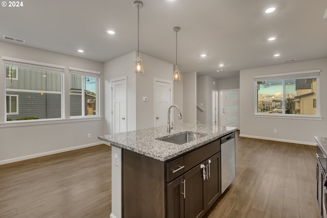 kitchen featuring dishwasher, pendant lighting, sink, dark brown cabinetry, and light stone counters