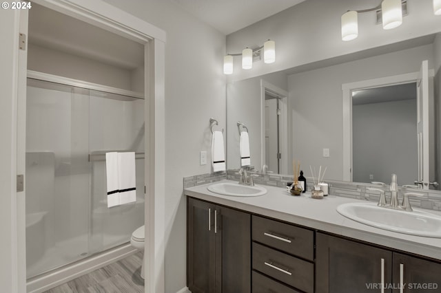 bathroom featuring wood-type flooring, toilet, vanity, and an enclosed shower