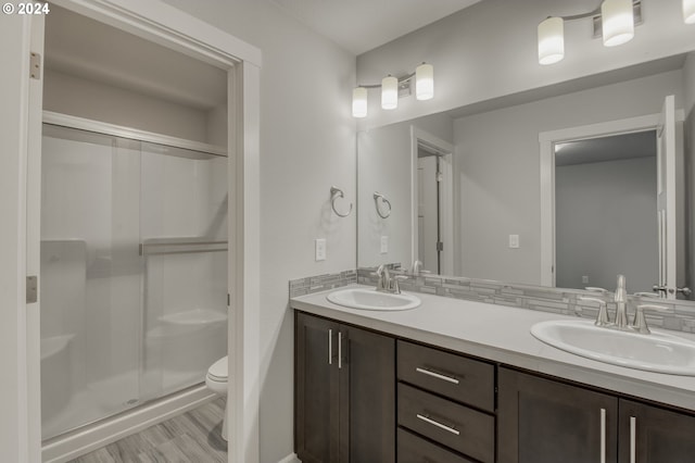 bathroom featuring a shower with shower door, hardwood / wood-style floors, toilet, and vanity