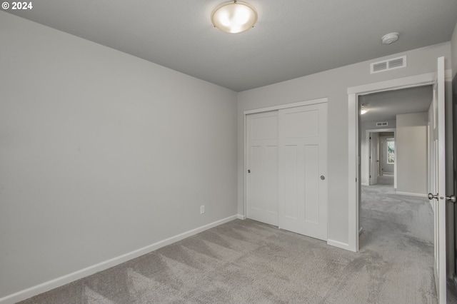 unfurnished bedroom featuring light colored carpet and a closet