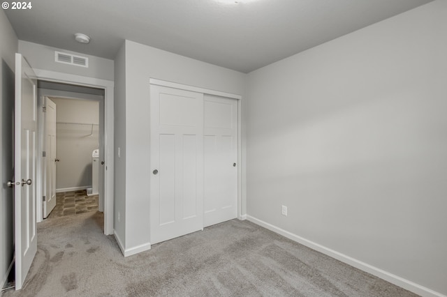 unfurnished bedroom featuring a closet and light colored carpet