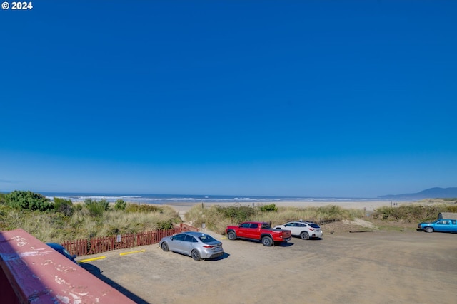 view of vehicle parking with a view of the beach and a water view