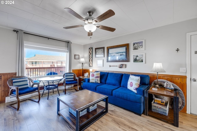 living room featuring ceiling fan, light hardwood / wood-style floors, and wooden walls