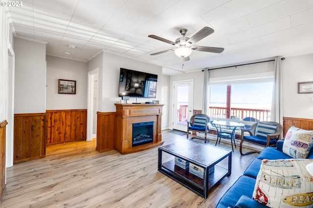 living room featuring crown molding, plenty of natural light, ceiling fan, and light wood-type flooring