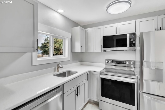 kitchen with stainless steel appliances, sink, and white cabinets