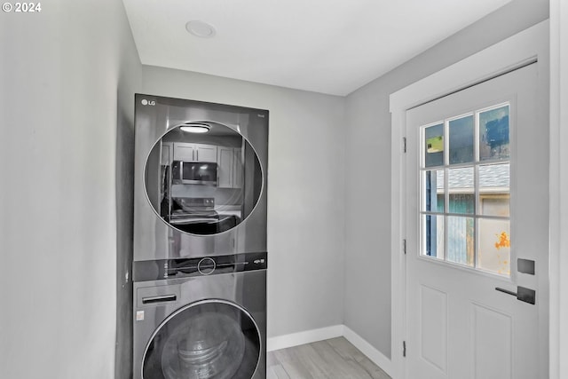 laundry area with stacked washing maching and dryer and light wood-type flooring