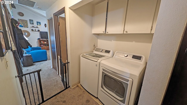 washroom featuring washer and dryer, a textured ceiling, light colored carpet, and cabinets