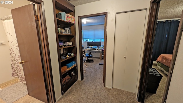 corridor featuring a textured ceiling and light carpet