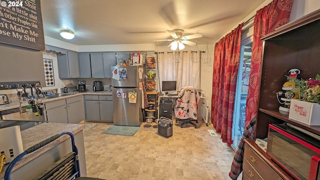 kitchen featuring stainless steel refrigerator, ceiling fan, and gray cabinetry