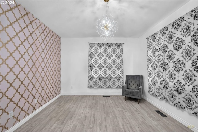 unfurnished room with hardwood / wood-style floors and a notable chandelier