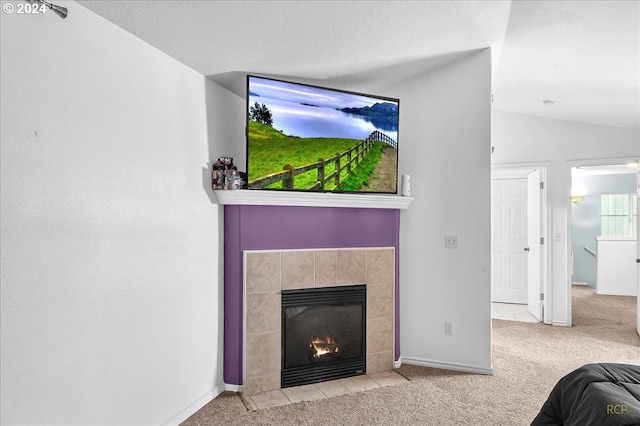 interior space with a textured ceiling, a tile fireplace, and lofted ceiling