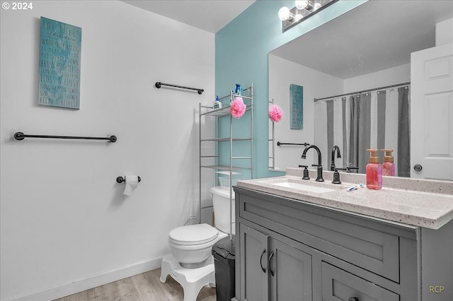 bathroom with hardwood / wood-style floors, toilet, walk in shower, and vanity