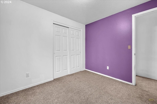 unfurnished bedroom featuring a textured ceiling, carpet flooring, and a closet