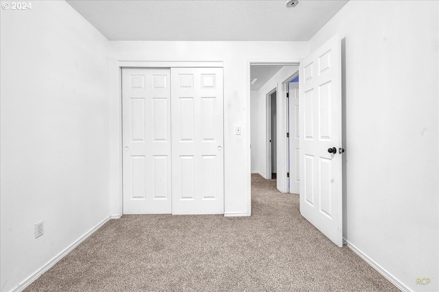 unfurnished bedroom with a closet and light carpet