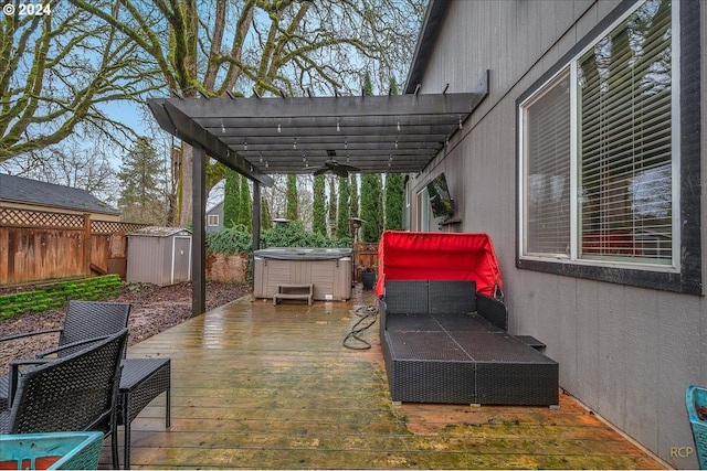 view of patio / terrace featuring a storage shed, a hot tub, a wooden deck, ceiling fan, and a pergola