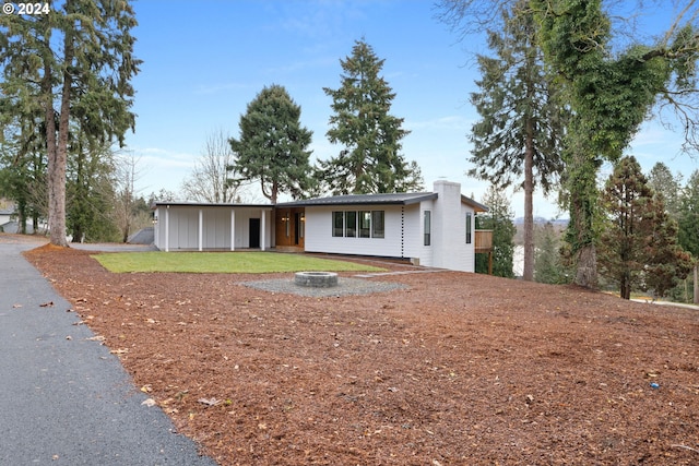 ranch-style house with an outdoor fire pit and a front lawn