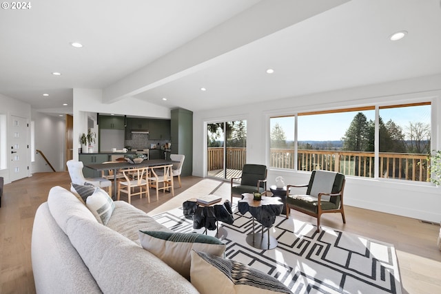 living room featuring light wood-type flooring and lofted ceiling with beams