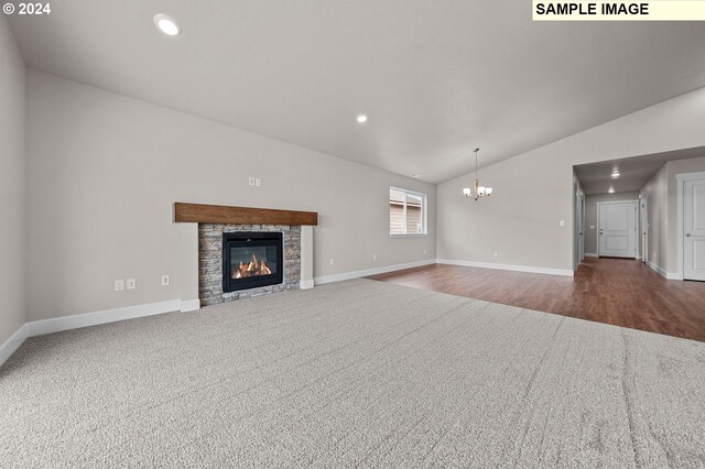 unfurnished living room featuring an inviting chandelier, vaulted ceiling, hardwood / wood-style flooring, and a stone fireplace