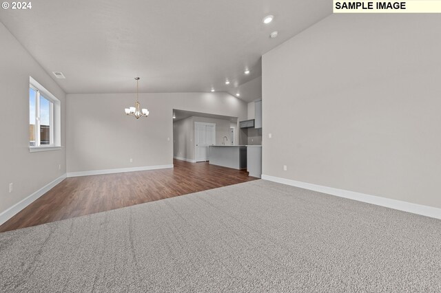 unfurnished living room with a notable chandelier, vaulted ceiling, sink, and dark hardwood / wood-style flooring