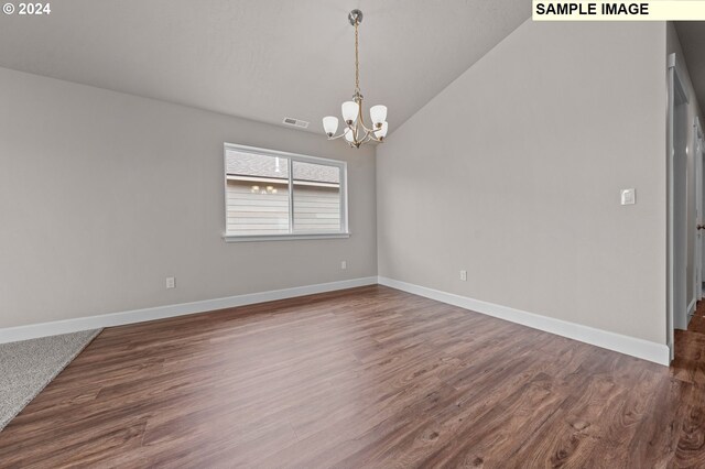 spare room featuring an inviting chandelier, lofted ceiling, and hardwood / wood-style floors