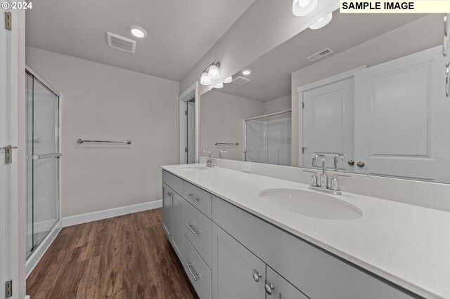 bathroom with wood-type flooring, a shower with door, and vanity