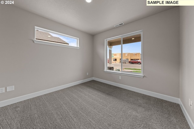 empty room featuring carpet floors, visible vents, and baseboards